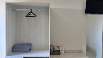 A compact room with a built-in wardrobe, a small desk, a chair, and a television.