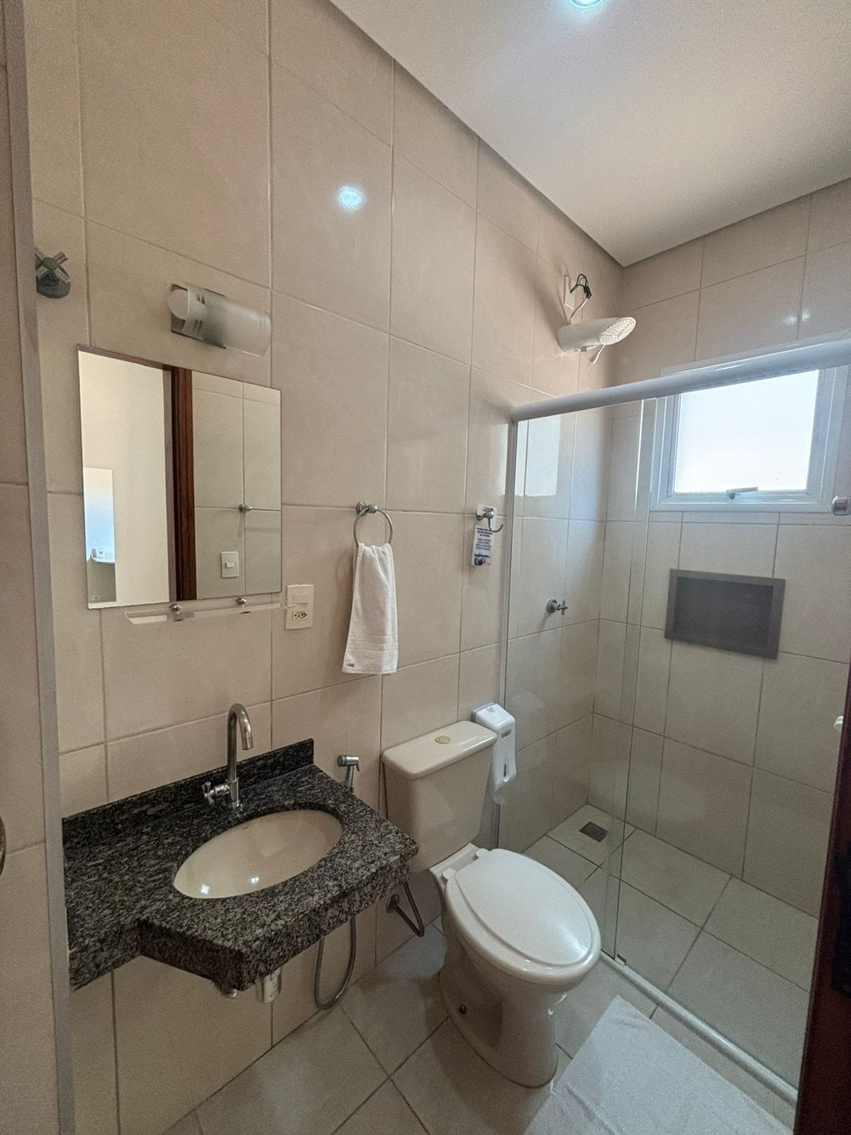 Un baño moderno con lavamanos de granito, inodoro, cabina de ducha y un espejo grande.