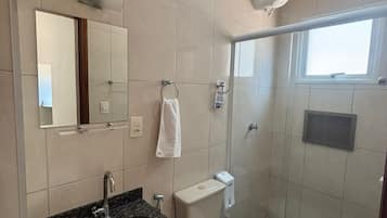 Un baño moderno con lavamanos de granito, inodoro, cabina de ducha y un espejo grande.