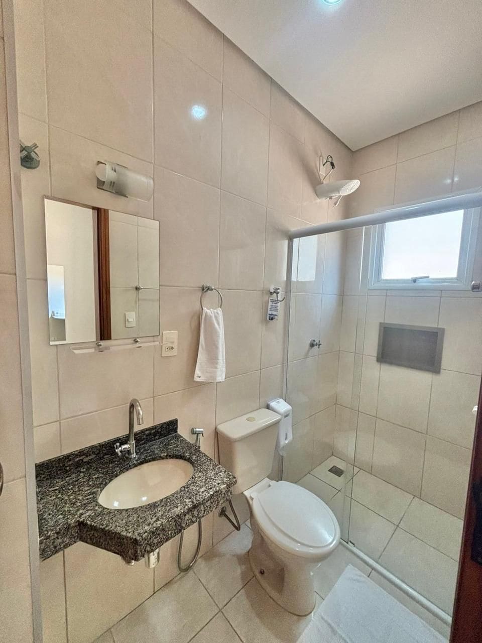 Ein modernes Badezimmer mit einem Granittischwaschbecken, einer Toilette und einer gläsernen Duschkabine.