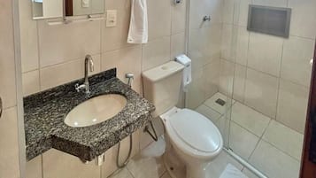 Ein modernes Badezimmer mit einem Granittischwaschbecken, einer Toilette und einer gläsernen Duschkabine.