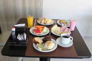 A breakfast table with plates of food, a juice glass, a coffee cup, and a napkin holder. - Hotel Galead (Santa Barbara d'Oeste)