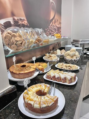 A buffet with various baked goods including cakes, cookies, and bread. - Hotel Galead (Santa Barbara d'Oeste)