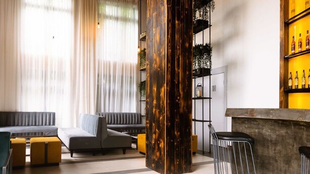 A modern living room with a grey sofa, yellow ottomans, and a wooden accent wall. - The Borough Lagos (Lekki)