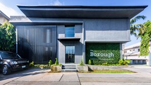 A modern building with a flat roof, large windows, and a green wall with 'The Borough' signage. - The Borough Lagos (Lekki)