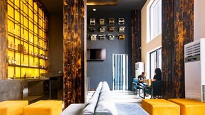 A modern hotel lobby with a long sofa, a bar area with bottles, and a wall displaying vintage typewriters. - The Borough Lagos (Lekki)