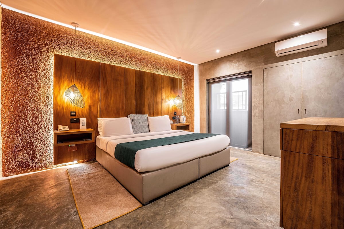 A modern bedroom with a large bed, wooden paneling, and a built-in wardrobe.