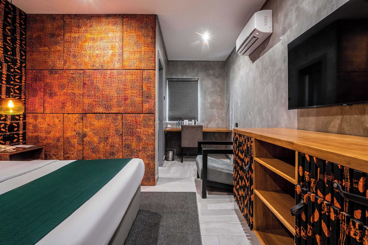 A hotel room with a bed, a desk, a TV, and a bathroom.