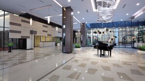 A spacious lobby with a grand piano, modern lighting, and a large glass wall. - Harper Palembang by ASTON (Palembang)