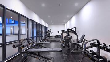 Un gimnasio moderno con máquinas de cardio, bancos de pesas y mancuernas.