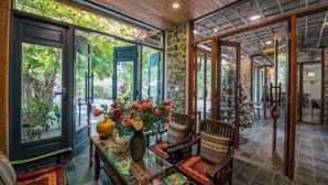 Una habitación acogedora con una mesa de vidrio, sillas y un jarrón de flores.