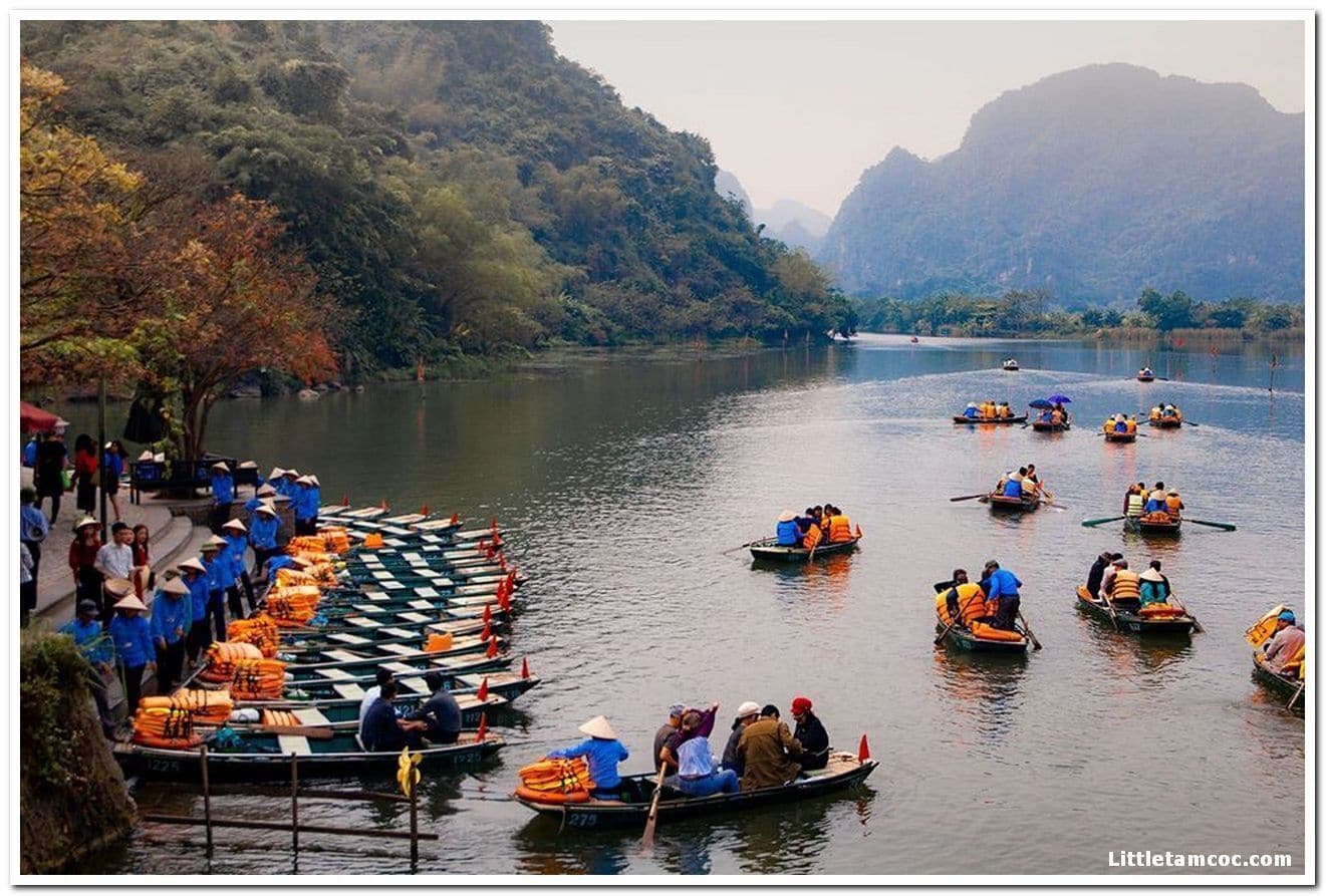 A river with boats and people, surrounded by hills.