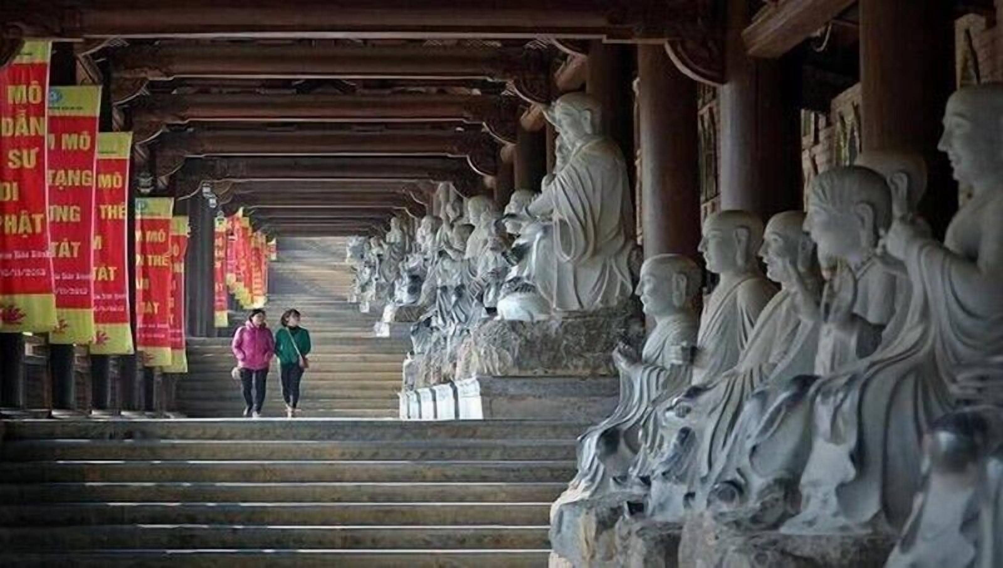 A corridor with statues and red banners.