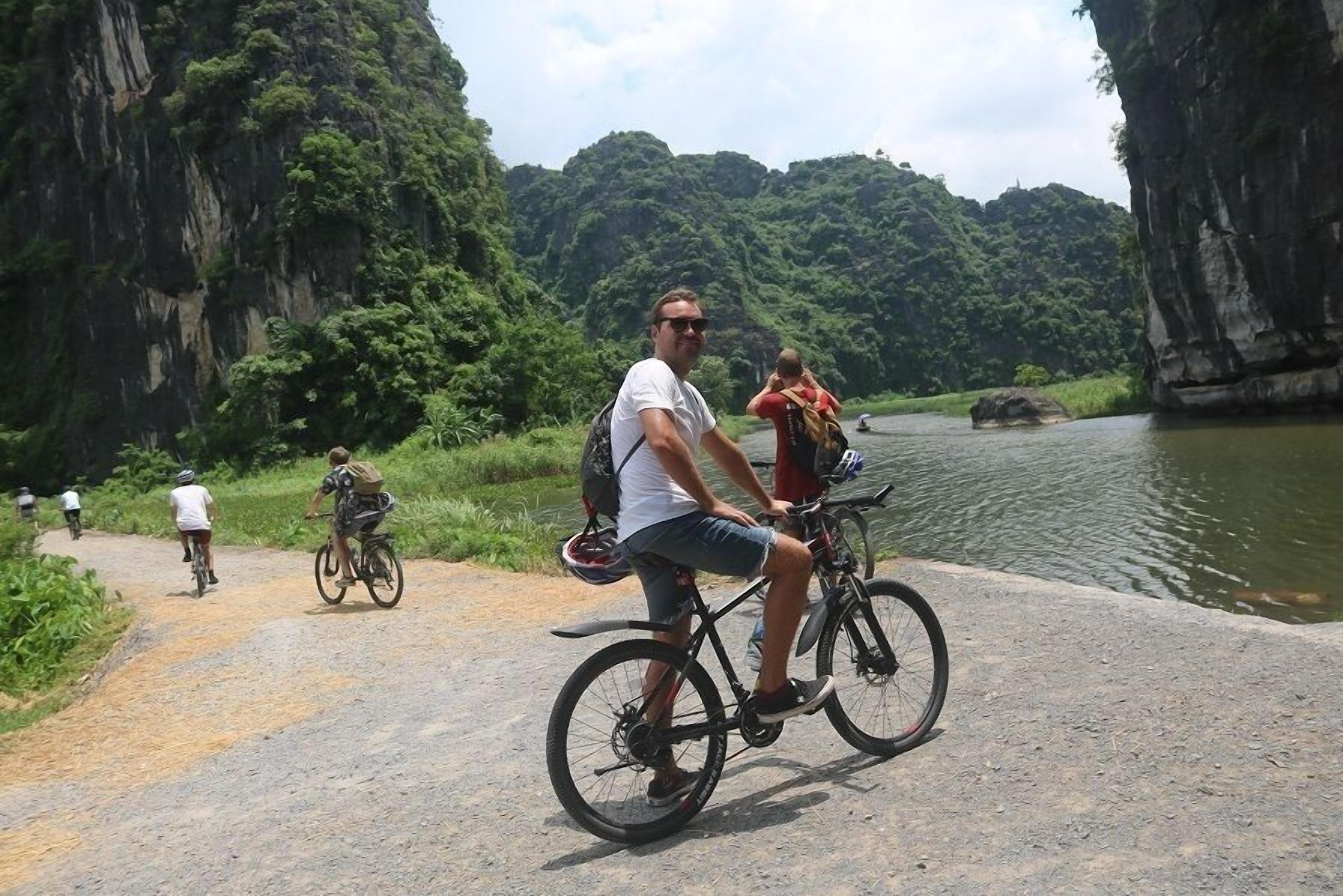 A paved path with cyclists and a body of water in the background.