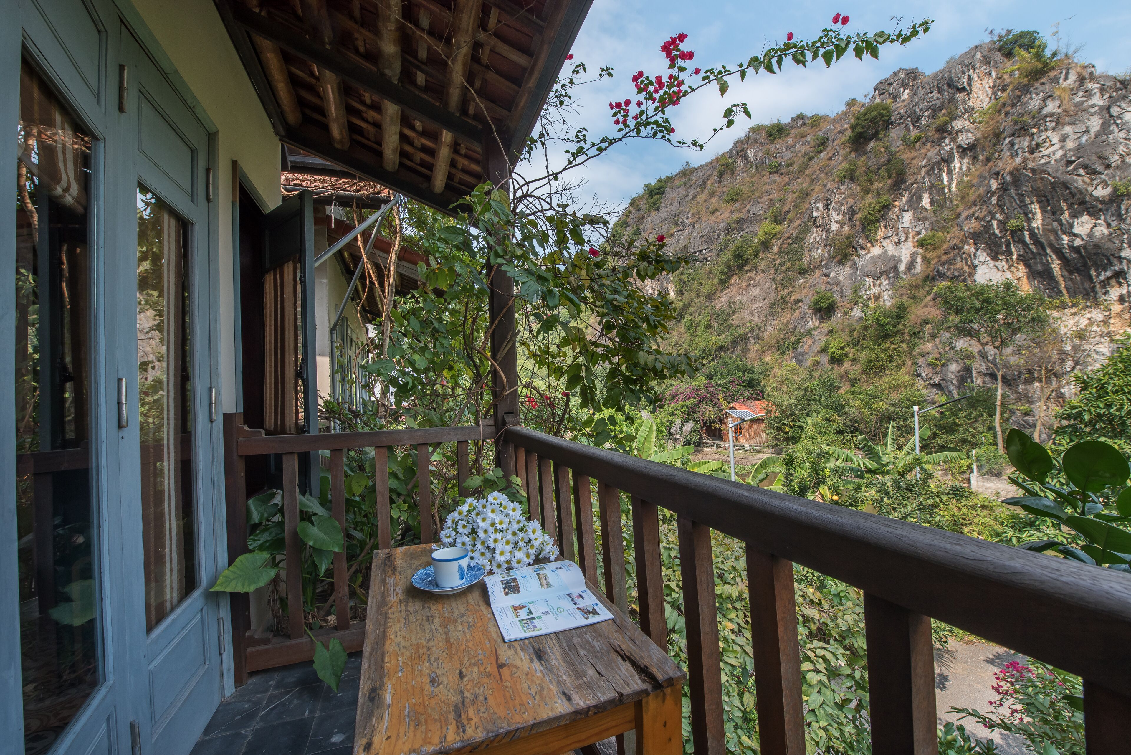 Un balcon en bois avec une table, une chaise et une vue sur un paysage montagneux.