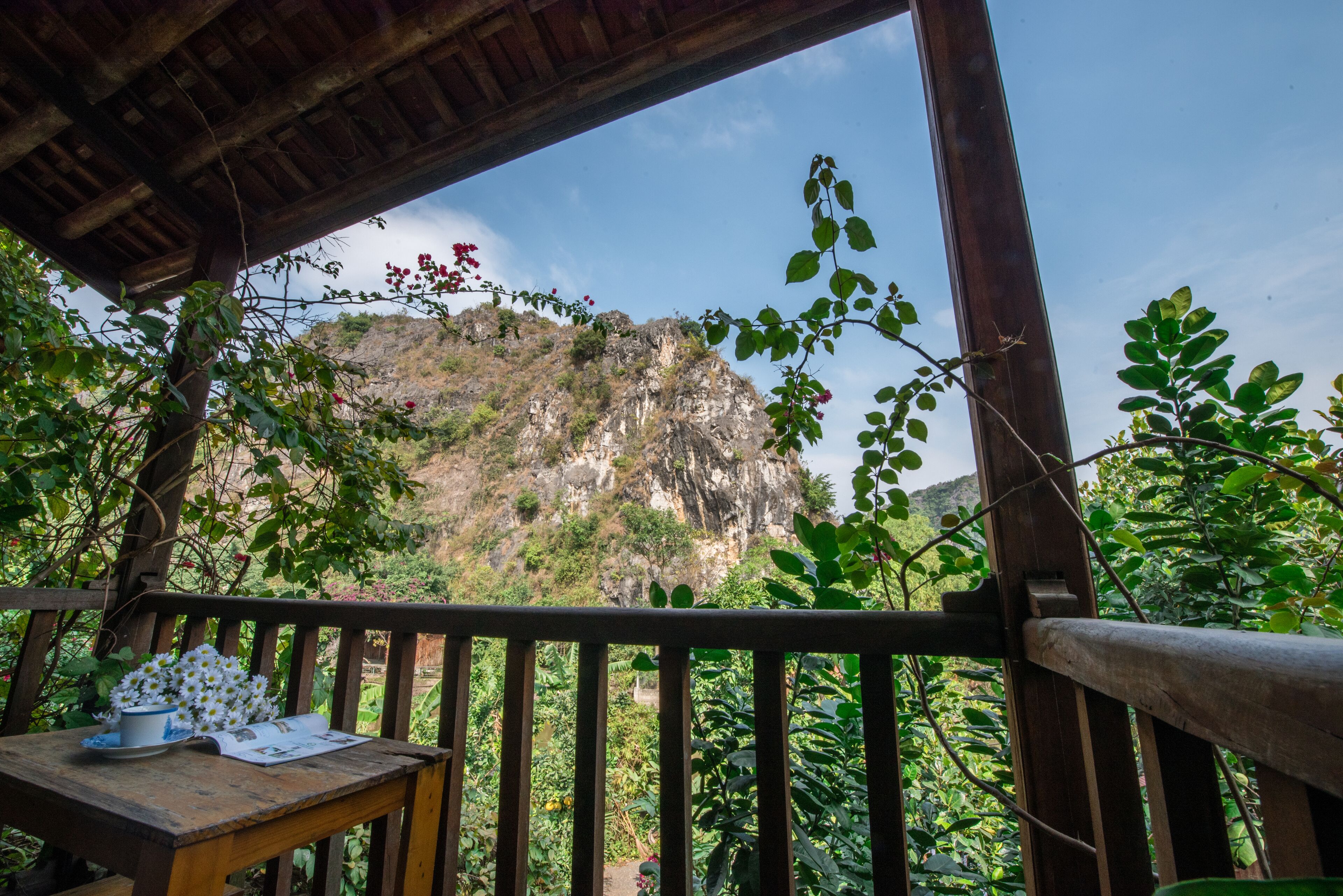 A wooden table with a menu and a cup, overlooking a mountainous landscape with a wooden railing.