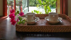 Una bandeja con dos tazas y una botella sobre una mesa junto a una ventana con vista a una montaña.