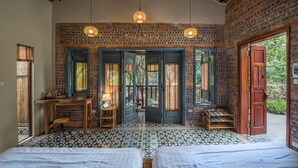 Una habitación con dos camas, un escritorio de madera, una lámpara y vistas al exterior.