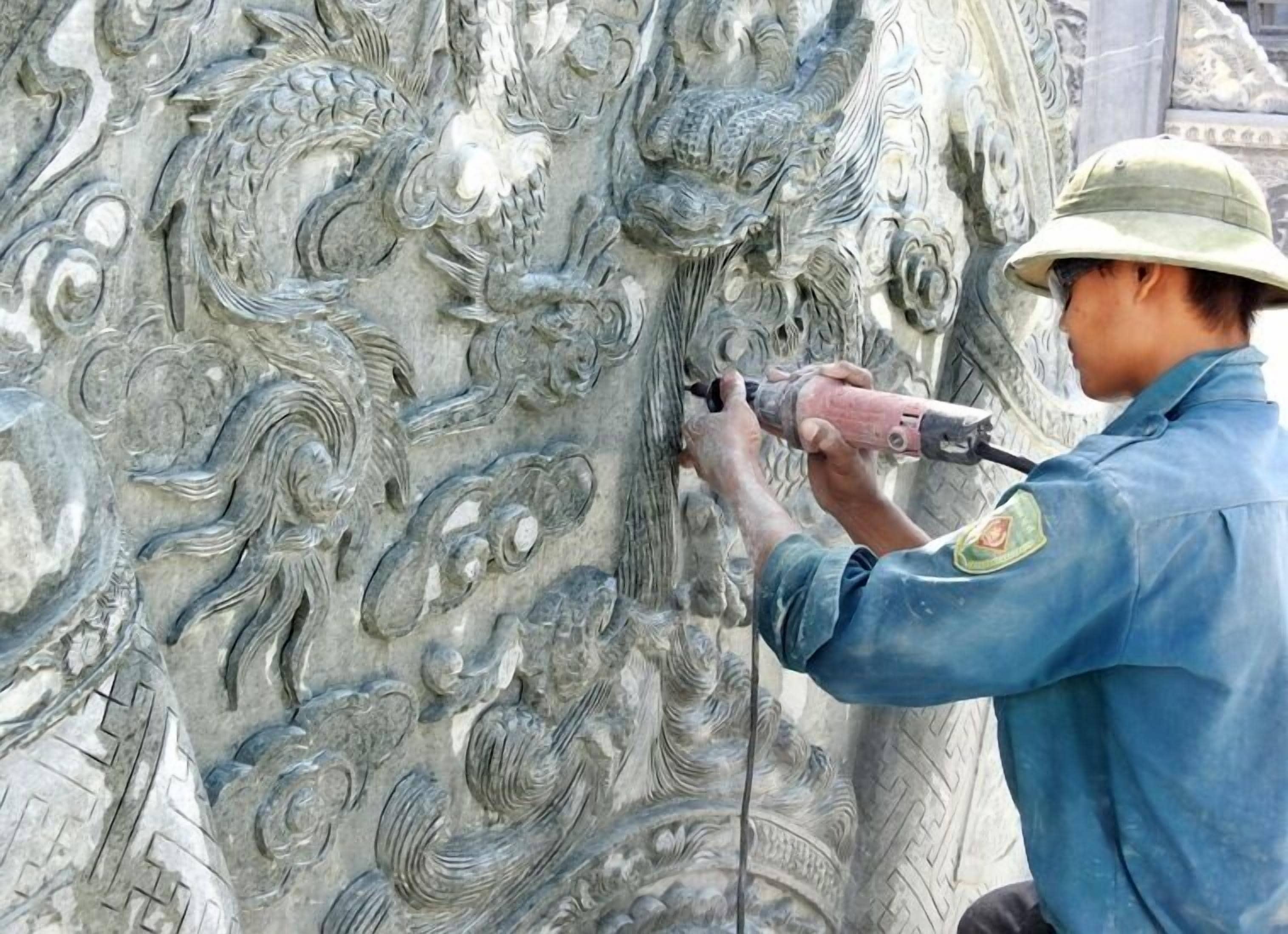 A person using a power tool on a detailed stone sculpture.