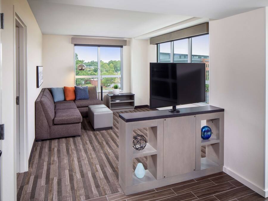 Sala moderna com sofá, TV e vista para o verde lá fora.