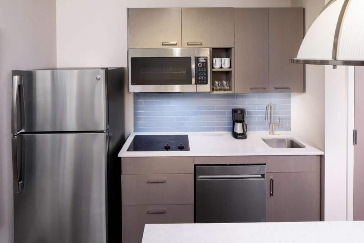 A modern kitchen with stainless steel appliances, a microwave, a coffee maker, and a dishwasher.