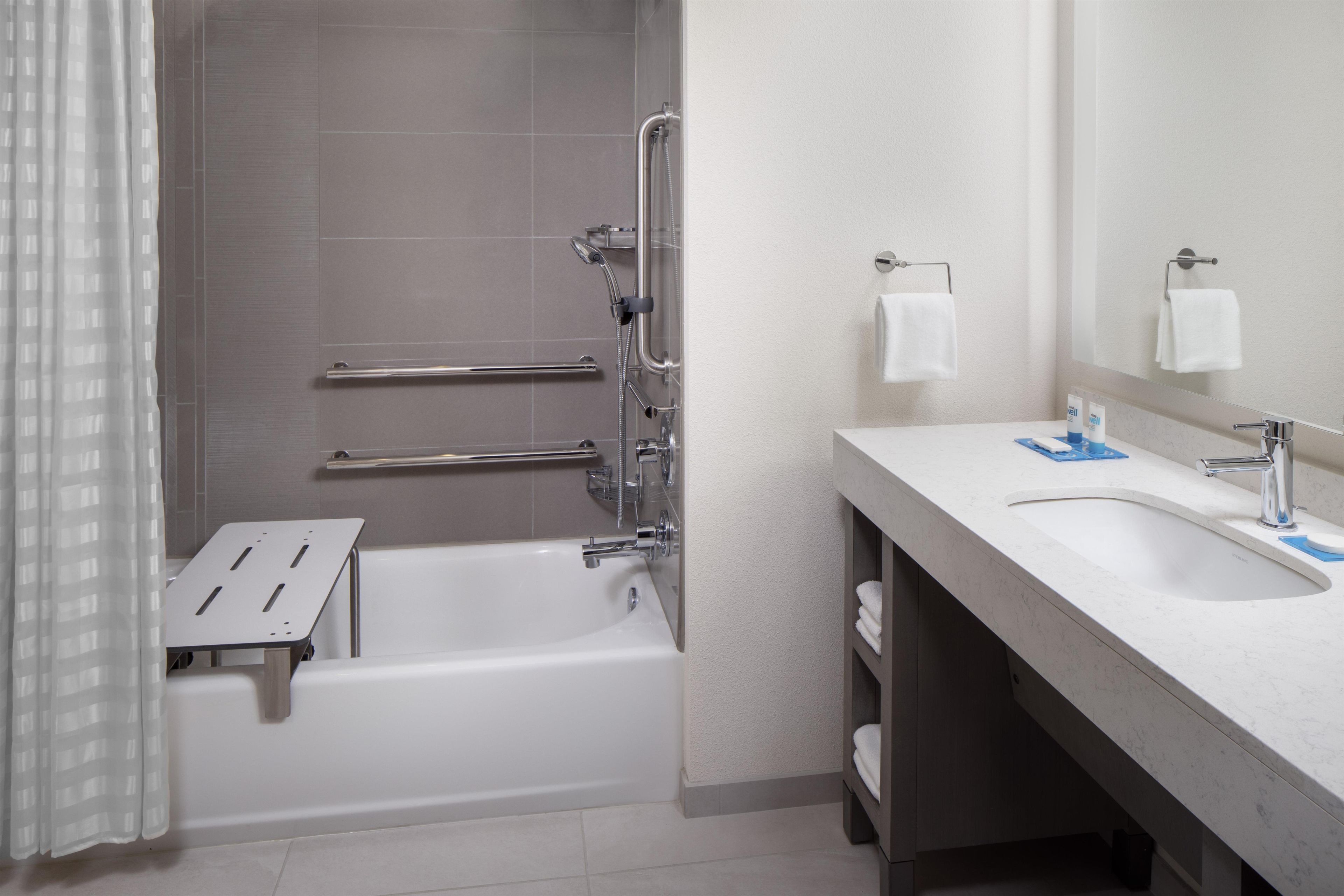 A modern bathroom with a bathtub, a shower, a vanity with a sink, and a mirror.