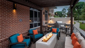 Eine Terrasse im Freien mit Backsteinmauern, einer Feuerstelle und Gartenmöbeln.