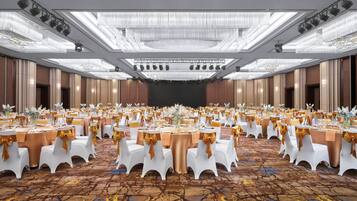 A large banquet hall with round tables, white chairs, and gold accents.