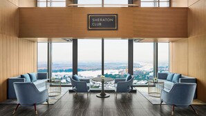 A Sheraton Club lounge with a large window view, two sofas, a coffee table, and a sign above the window. - Sheraton Hai Phong (Hai Phong)