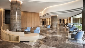 A spacious lobby with a curved seating area, a reception desk, and a view of the outdoors. - Sheraton Hai Phong (Hai Phong)