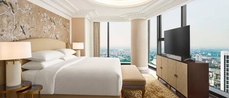 A spacious bedroom with a large bed, a TV, and a view of the city.