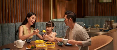 A family dining at a restaurant with a wooden interior and blue upholstered seating.