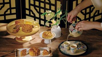 Uma mesa com doces, um bule de chá e um vaso de flores.