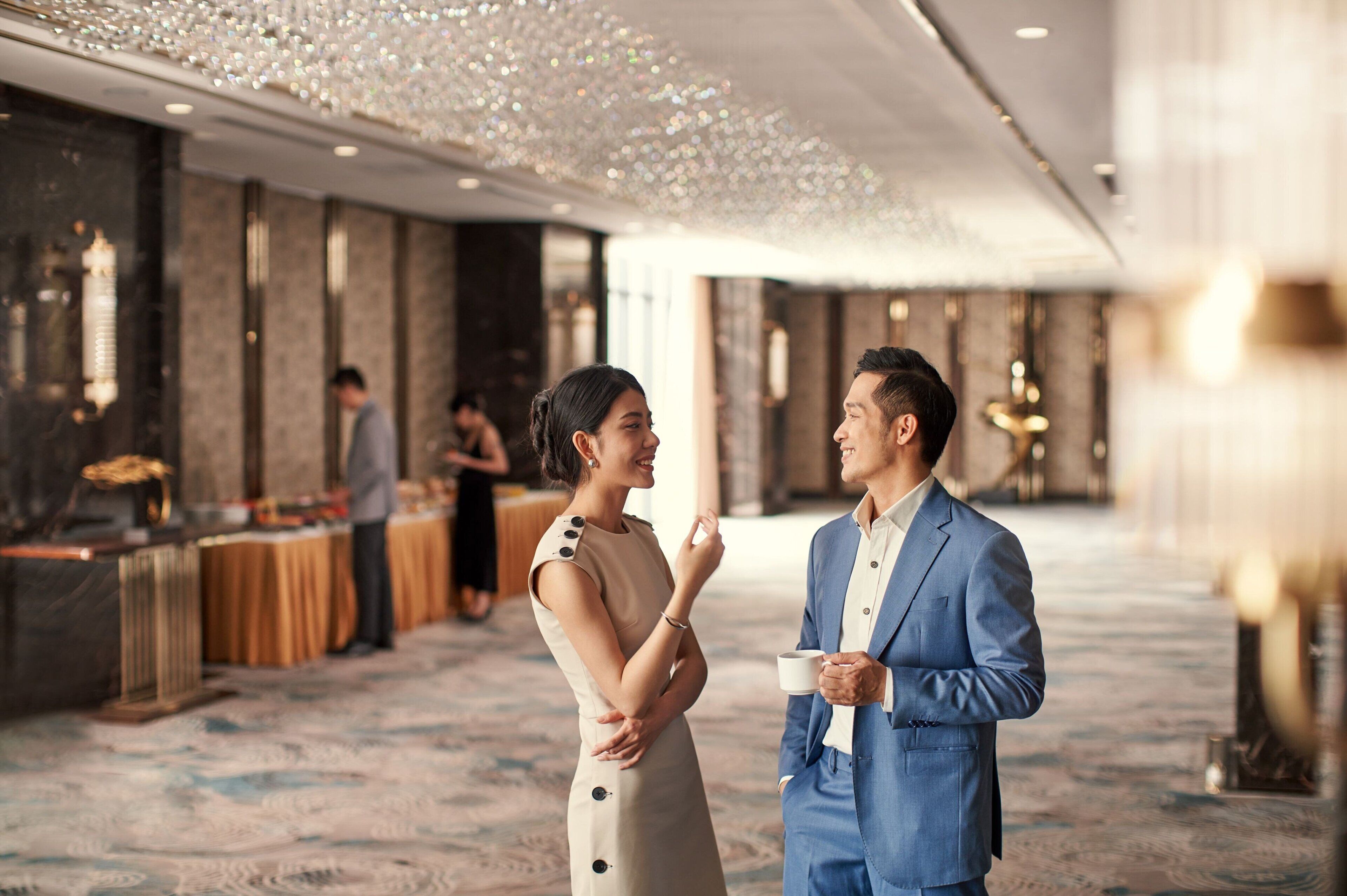 A spacious lobby with a marble floor and a high ceiling with decorative lighting.
