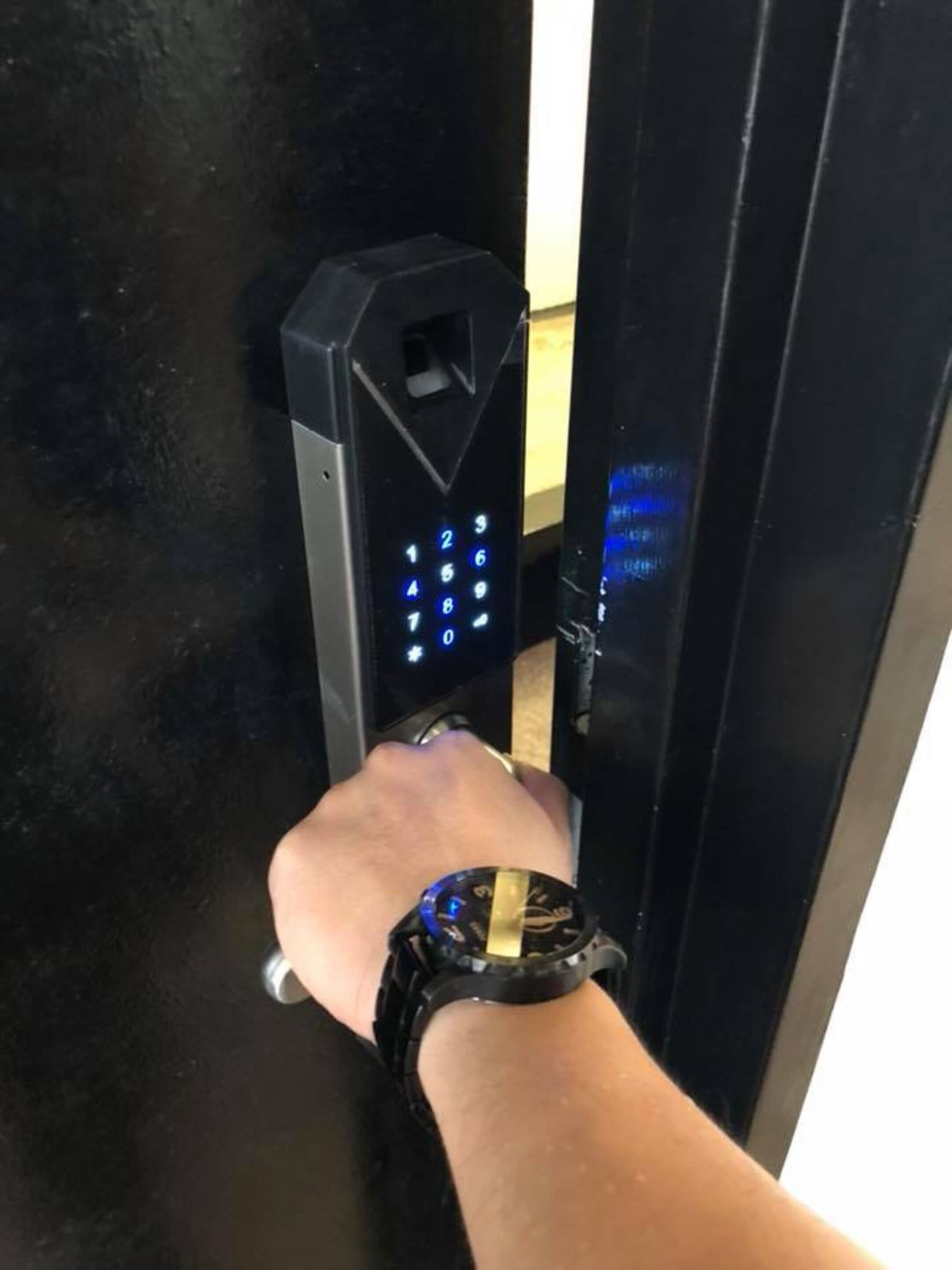 Une main utilisant un pavé numérique pour saisir un code sur un verrou de porte.