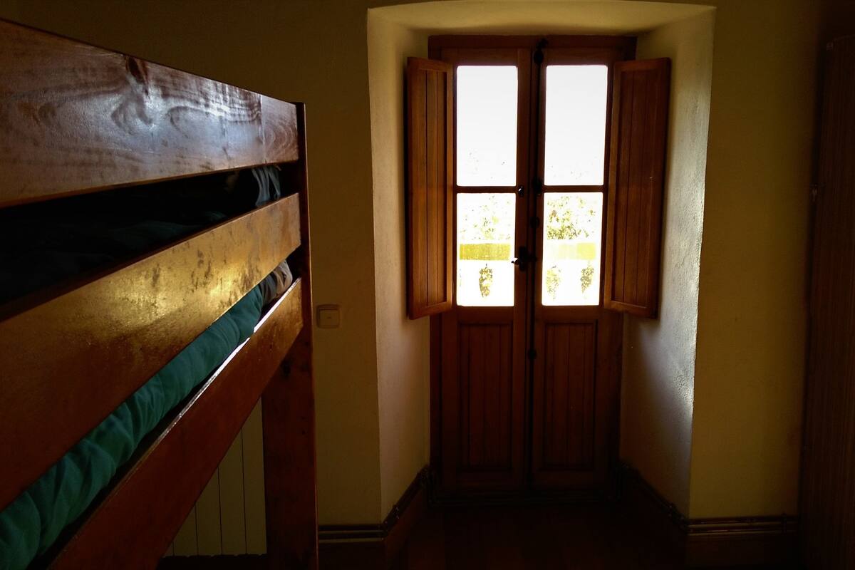 A narrow hallway with wooden doors and a bench on the left.