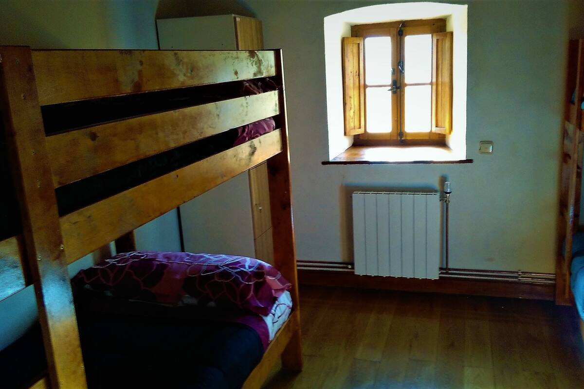 A bunk bed room with a window and radiator.