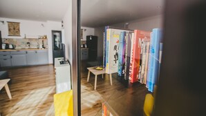 A modern living room with a glass partition, a wooden floor, and a bookshelf with various books. - Komplex Apartamenty Europa Sosnowiec (Sosnowiec)