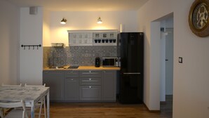 A compact kitchen with grey cabinets, a black refrigerator, a microwave, and a sink. There are two pendant lights above the countertop. - Komplex Apartamenty Europa Sosnowiec (Sosnowiec)