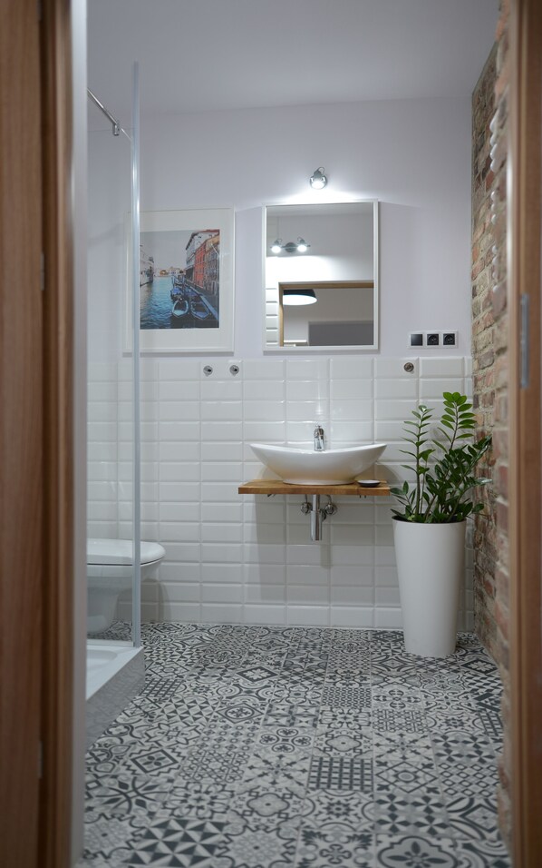 A modern bathroom with a white sink, a mirror, and a potted plant. - Komplex Apartamenty Europa Sosnowiec (Sosnowiec)