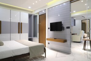 Ein modernes Schlafzimmer mit Bett, Kleiderschrank, Fernseher und Sitzecke.
