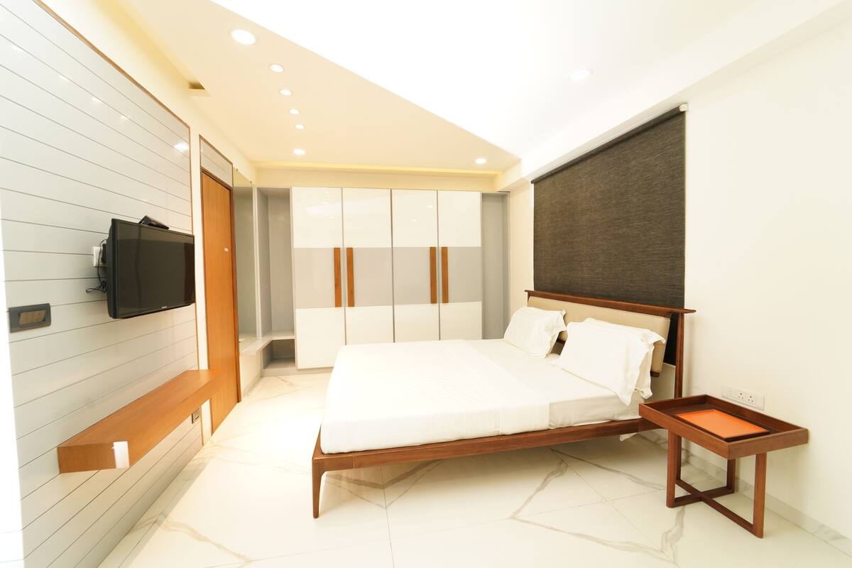 Un dormitorio moderno con una cama de madera, un televisor montado en la pared y un armario con puertas correderas.