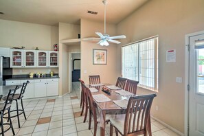 A dining area with a large table, chairs, and a ceiling fan.