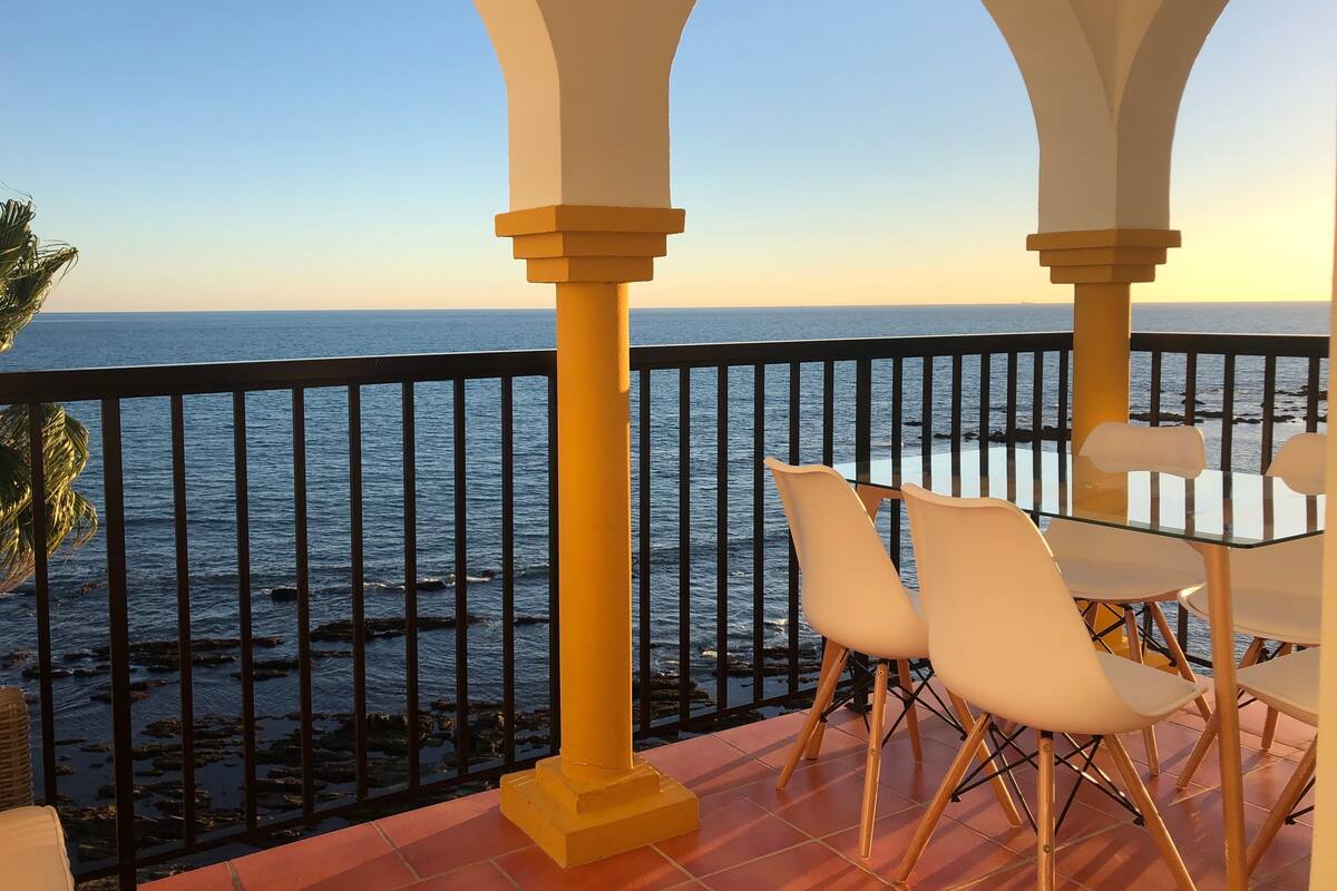 Un balcón con vistas al mar, con una mesa y sillas.