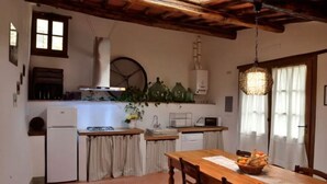 A rustic kitchen with a wooden table, a refrigerator, a sink, and a stove. - The Porchereccia delle Bartaline (Panzano in Chianti)