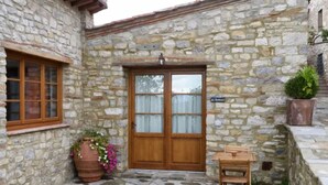 A stone building with a wooden door and windows, a small table, and a potted plant. - The Porchereccia delle Bartaline (Panzano in Chianti)