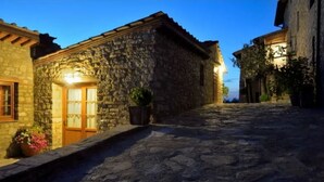 A stone building with a wooden door and window, a stone staircase, and a paved street. - The Porchereccia delle Bartaline (Panzano in Chianti)