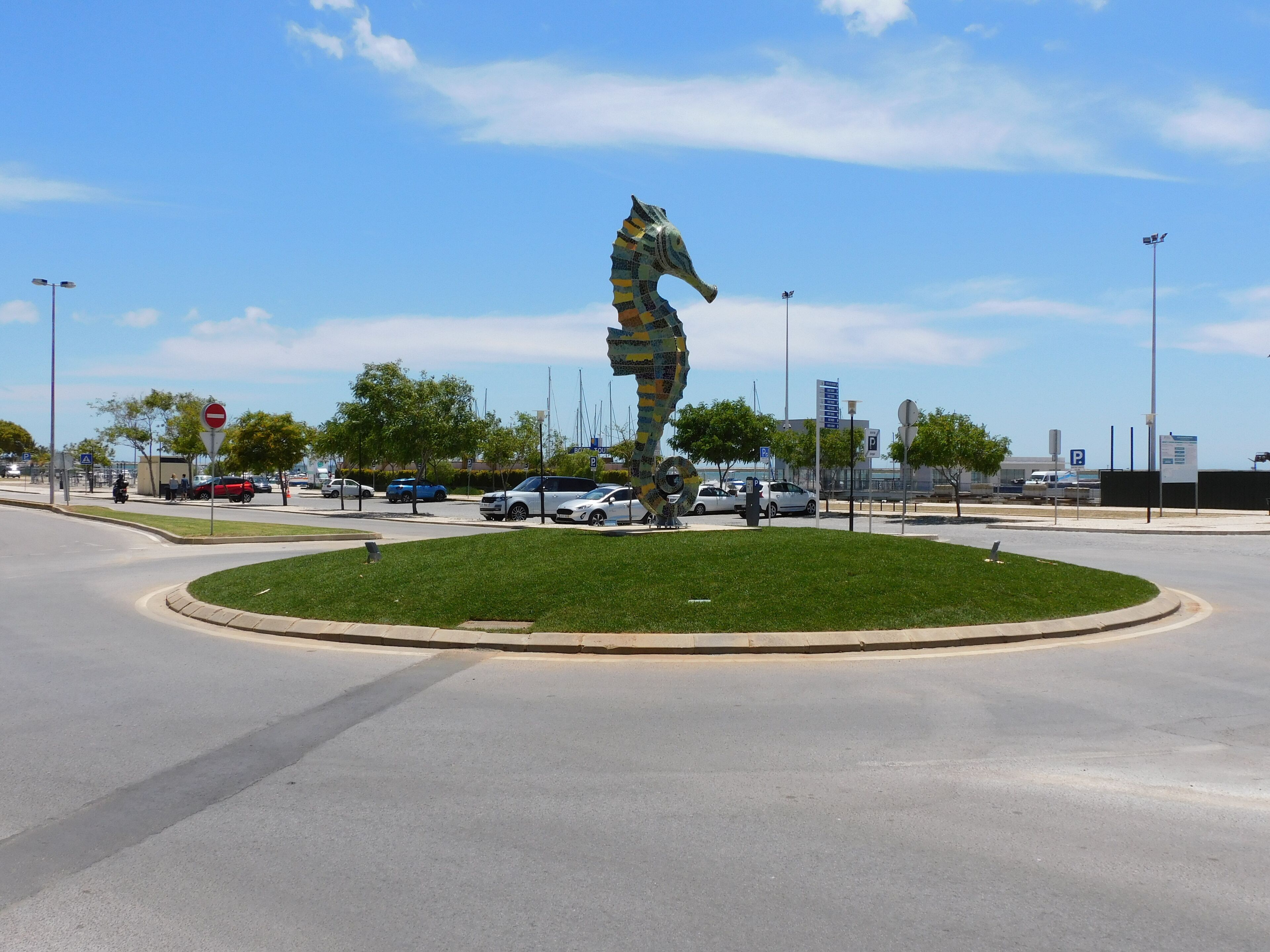 A roundabout with a sculpture of a horse in mid-gallop, surrounded by a grassy area.