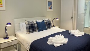 A neatly made bed with a dark blue bedspread and white pillows, two bedside lamps, and a framed picture on the wall. - Lovely spacious 2 bedroom, 2 bathroom Mews Cottage, Glasgow (Glasgow)