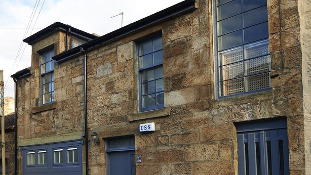 A two-story stone building with a blue garage door, a small balcony, and a clear sky. - Lovely spacious 2 bedroom, 2 bathroom Mews Cottage, Glasgow (Glasgow)